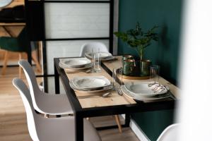 a dining room table with plates and glasses on it at Green Loft Apartament in Biała Podlaska +8 photos