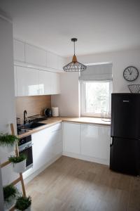 een keuken met witte kasten en een zwarte koelkast bij Green Loft Apartament in Biała Podlaska