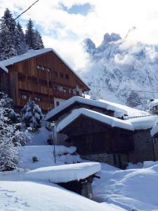 a building covered in snow with mountains in the background at Tabià Alleghe vista lago, monte Civetta Dolomiti in Alleghe