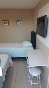 a bedroom with a bed and a table and a chair at Pousada São Pedro in São Pedro da Aldeia