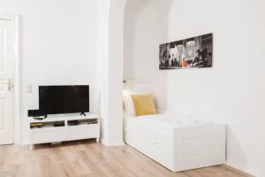 a white living room with a flat screen tv at Family Apartment for 6 guests, Mitte Moabit in Berlin