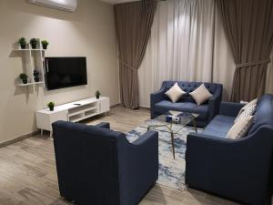 a living room with two blue couches and a tv at Makarem Hotel Apartment - مكارم للشقق الفندقية in Riyadh