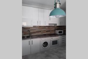 a kitchen with white cabinets and a washer and dryer at Primera linea playa, vista espectacular in El Médano