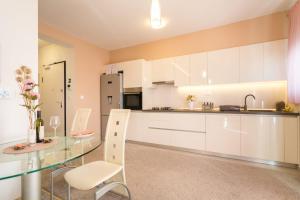 cocina con mesa de cristal y armarios blancos en Apartment SARA - free parking for 2 cars en Zagreb