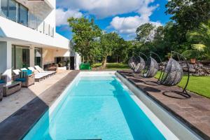 a swimming pool with chairs next to a house at Villa Maya- Luxury Mansion in Akumal