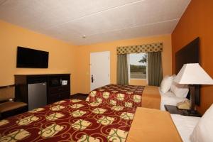 a hotel room with two beds and a television at Budgetel Inn Glens Falls-Lake George-Saratoga in Glens Falls