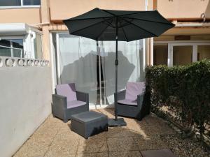 two chairs and an umbrella in front of a building at STUDIO MEUBLE 30 M2 LA LONDE LES MAURES , 900 M DES PLAGES in La Londe-les-Maures