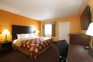 a hotel room with a bed and a desk at Budgetel Inn Glens Falls-Lake George-Saratoga in Glens Falls