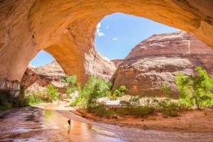 a person walking in a river under a bridge at Red Rock Ranch Log Cabin: Large, Fully Furnished in Escalante
