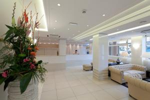 eine Lobby mit Sofas und Blumen in einem Gebäude in der Unterkunft Hôtel Paradis in Lourdes