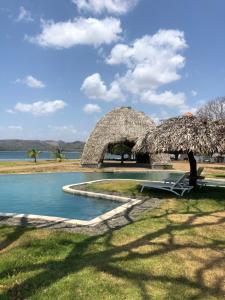 a resort with a pool and a straw umbrella at Azuero Lodge: Luxury Beachfront condo- Playa Venao in Playa Venao