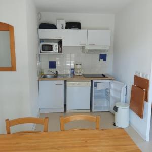 a kitchen with white appliances and a table and chairs at Résidence mille soleils in Font-Romeu