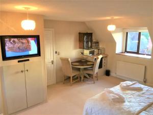 a room with a bed and a table and a television at Hartpury B&B in Hartpury