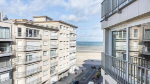 une vue sur la plage depuis le balcon d'un immeuble dans l'établissement Zonnig en gezellig appartement met zijdelings zeezicht en zwembad in Koksijde, à Coxyde