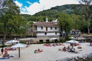 a group of people sitting on a beach with umbrellas at Casinha dos Figueirais in Góis