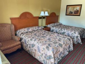 a hotel room with two beds and a chair at Western Motel - Jesup in Jesup