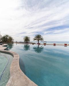 een zwembad met palmbomen en de oceaan bij Playa de La Paz in La Paz
