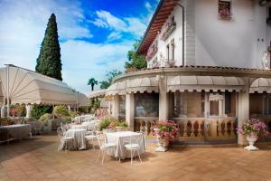 un restaurante con mesas y sillas blancas frente a un edificio en Park Hotel Ville Montefiori, en Gardone Riviera