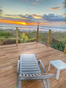 une chaise blanche assise sur une terrasse avec vue sur l'océan dans l'établissement Résidence Paradis Tropical, à Basse-Terre