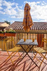 einen Tisch und zwei Stühle und einen Regenschirm auf einer Terrasse in der Unterkunft The Little House in Bormes-les-Mimosas