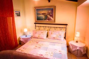 a bedroom with a bed with two tables and a painting at Alessandro in Sidari