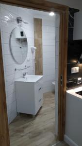 W białej łazience znajduje się umywalka i lustro. w obiekcie Apartamenty U Iwony Centrum miasta blisko Parku Zdrojowego w Kudowie Zdroju