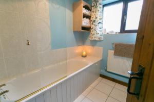 a bathroom with a bath tub with a candle in it at Erw Fach in Valley +11 photos