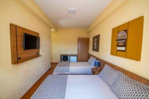 a hotel room with two beds and a flat screen tv at Imperador Hotel in Poços de Caldas