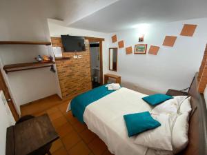 a bedroom with a large bed with blue pillows at Hotel - Hospedería Villa Palva in Villa de Leyva