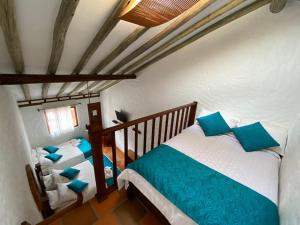 two beds in a room with blue pillows at Hotel - Hospedería Villa Palva in Villa de Leyva