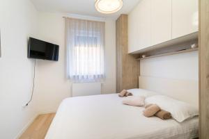 1 dormitorio con 1 cama blanca y TV en la pared en Apartment SARA - free parking for 2 cars en Zagreb