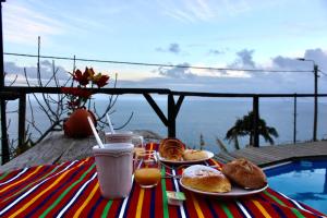 a table with breakfast food and a view of the ocean at Quarto vista mar in Câmara de Lobos