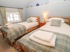 a bedroom with two beds and a window at Robyn Cottage in Budleigh Salterton