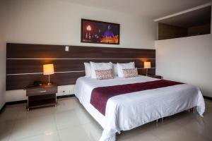 1 dormitorio con 1 cama blanca grande y cabecero de madera en Hotel San Martin Popayan, en Popayán