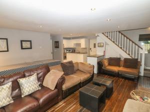 a living room with a brown leather couch and a staircase at Heythrop in Alton