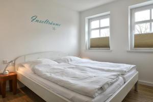 Cama blanca en habitación con 2 ventanas en Stadtwohnung 1, en Wyk auf Föhr