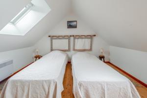 two beds in a room with white walls at Maison charmante avec vue sur la mer à Paimpol in Paimpol