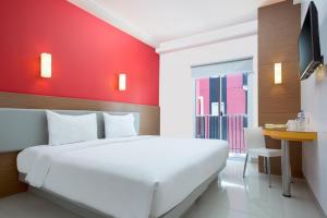 a white bed in a room with a red wall at Amaris Hotel Kupang in Kupang
