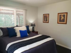 Un dormitorio con una cama con almohadas azules y una ventana en Tyenna River Cottages, en Tyenna