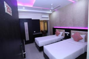 two beds in a hotel room with purple lights at Shri Subham Residency in Srīrangam