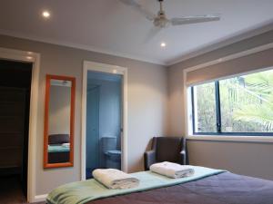 a bedroom with a bed and a window and a mirror at Beachside Holiday Home with Stunning Seaviews in Avoca Beach