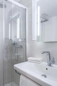 ein weißes Bad mit einem Waschbecken und einer Dusche in der Unterkunft Hotel Haus Delecke in Möhnesee