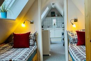 Habitación pequeña con 2 camas con almohadas rojas. en Kuscheliges Sylt Zuhause für 2 Personen en Westerland