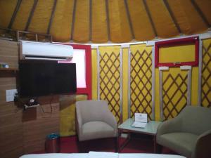 Zimmer mit einem TV, einem Stuhl und einem Tisch in der Unterkunft Rick Resort Teluk Intan in Teluk Intan