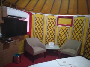 Zimmer mit 2 Stühlen und einem TV in einer Jurte in der Unterkunft Rick Resort Teluk Intan in Teluk Intan