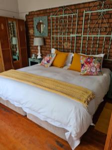 a large white bed with yellow pillows on it at Mirabel Guesthouse in Parys