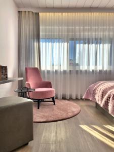 - une chambre avec une chaise rose et un lit dans l'établissement ART-Hotel Braun, à Kirchheimbolanden