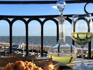 ein Glas Wein auf einem Tisch mit Meerblick in der Unterkunft Moray Hastings in Hastings
