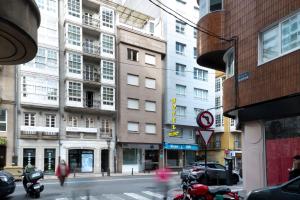 une rue urbaine avec des bâtiments et une personne traversant la rue dans l'établissement Hotel Nido, à La Corogne