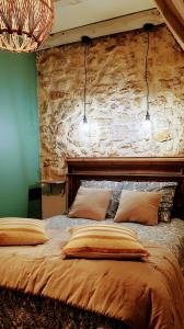 a bedroom with a large bed with a stone wall at Gîte et chambres d'hôtes - Sur le chemin des sens in Azerat